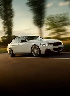 White car driving on a country road in the sunset