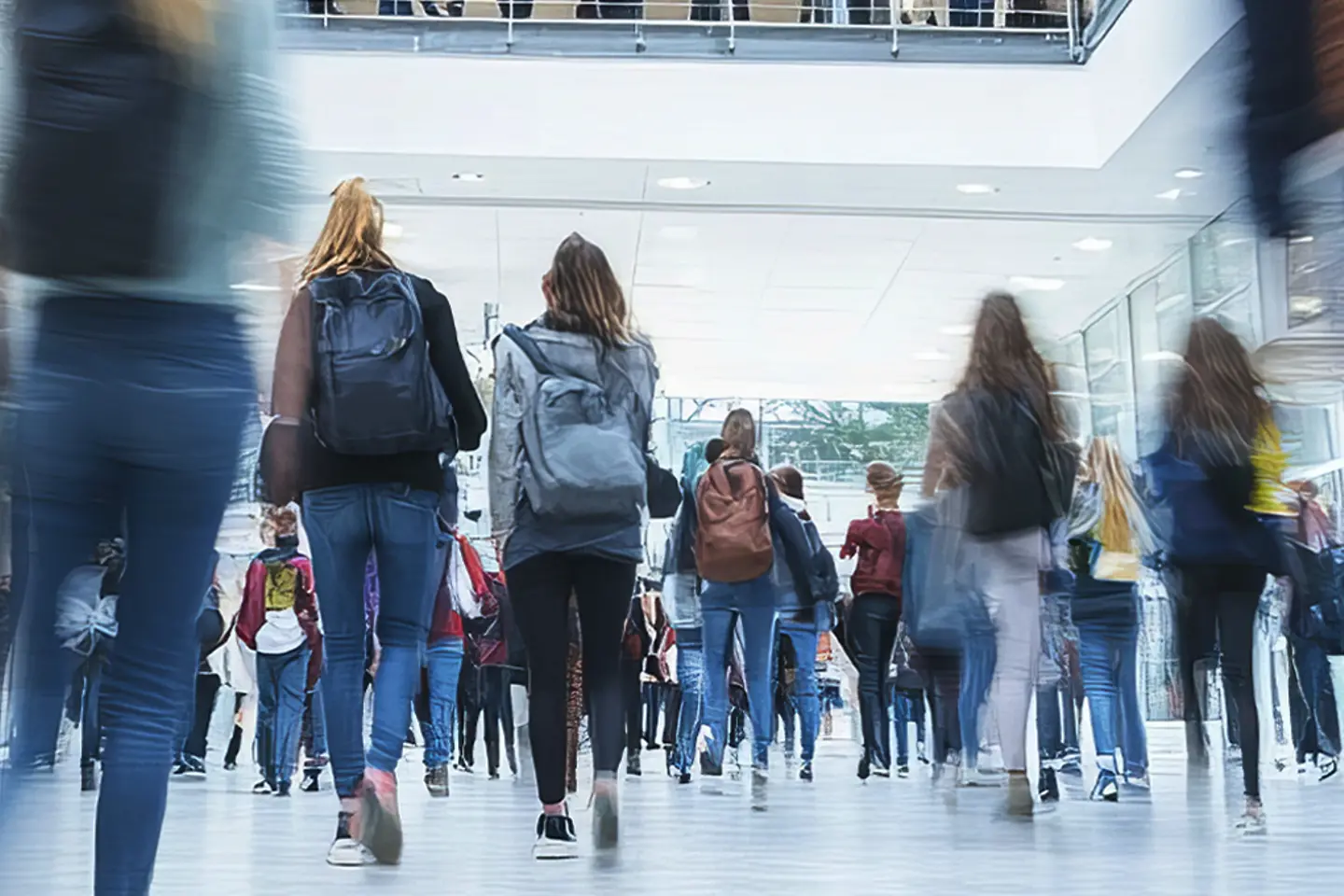  Gymnasiasten gehen zwischen den Unterrichtsstunden in einem belebten Schulgebäude die Treppe hinauf