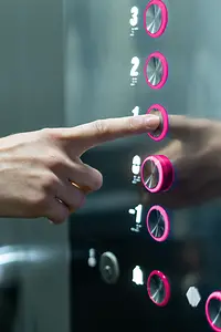 Person in an elevator pushing magenta button