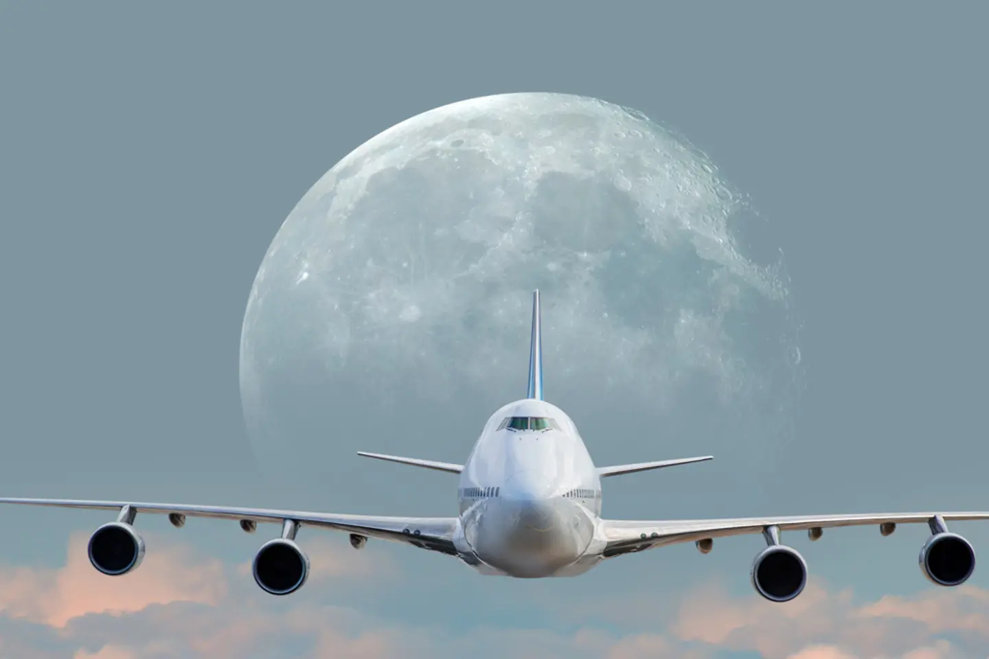 Ein weißes Passagierflugzeug über den Wolken bei Vollmond