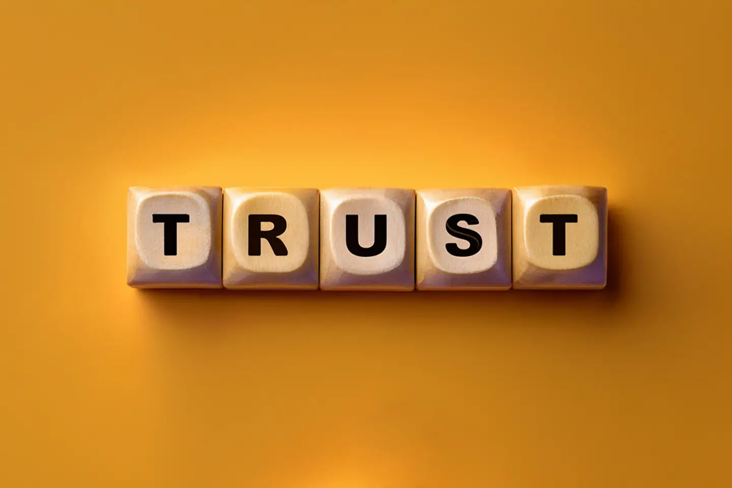 Cinco cubos sobre fondo amarillo con las letras TRUST
