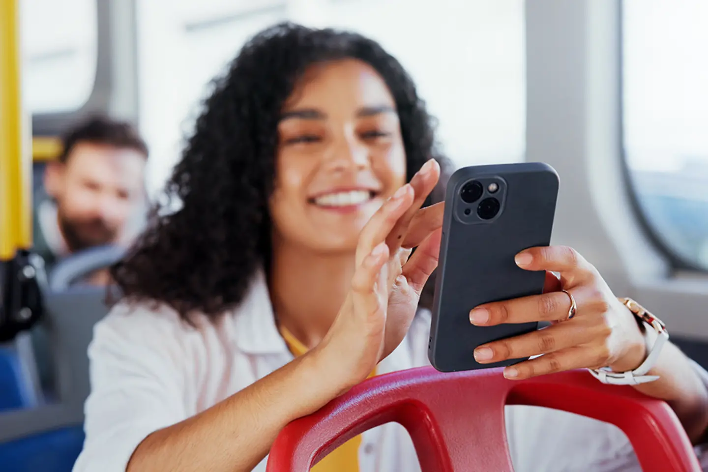 A woman is riding the bus and typing on a cell phone.
