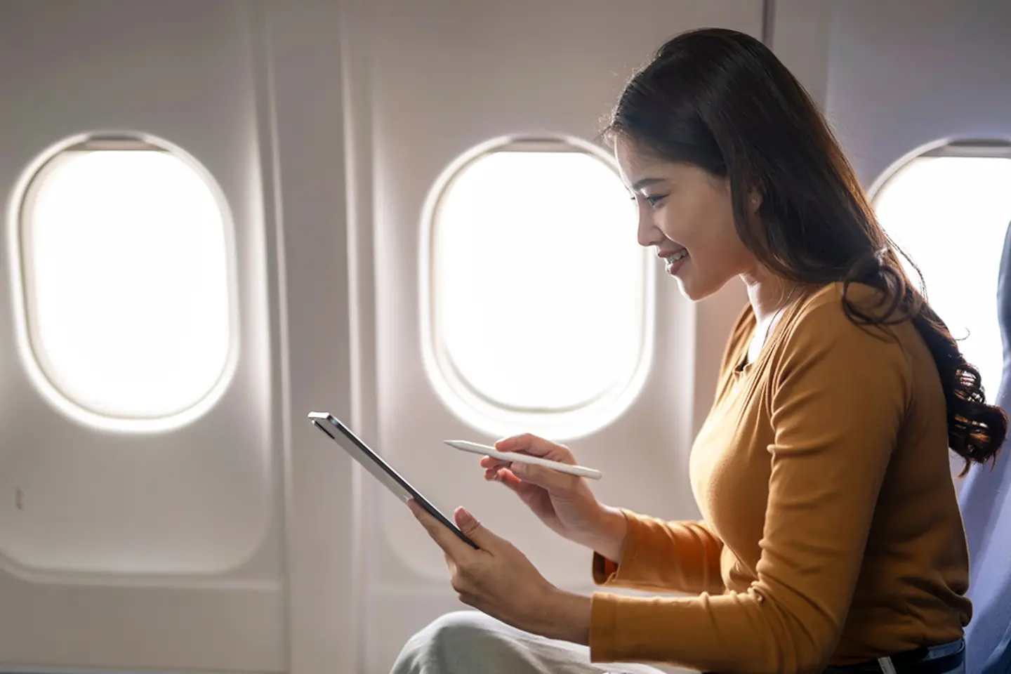 Joven empresaria trabajando con una tablet en un avión
