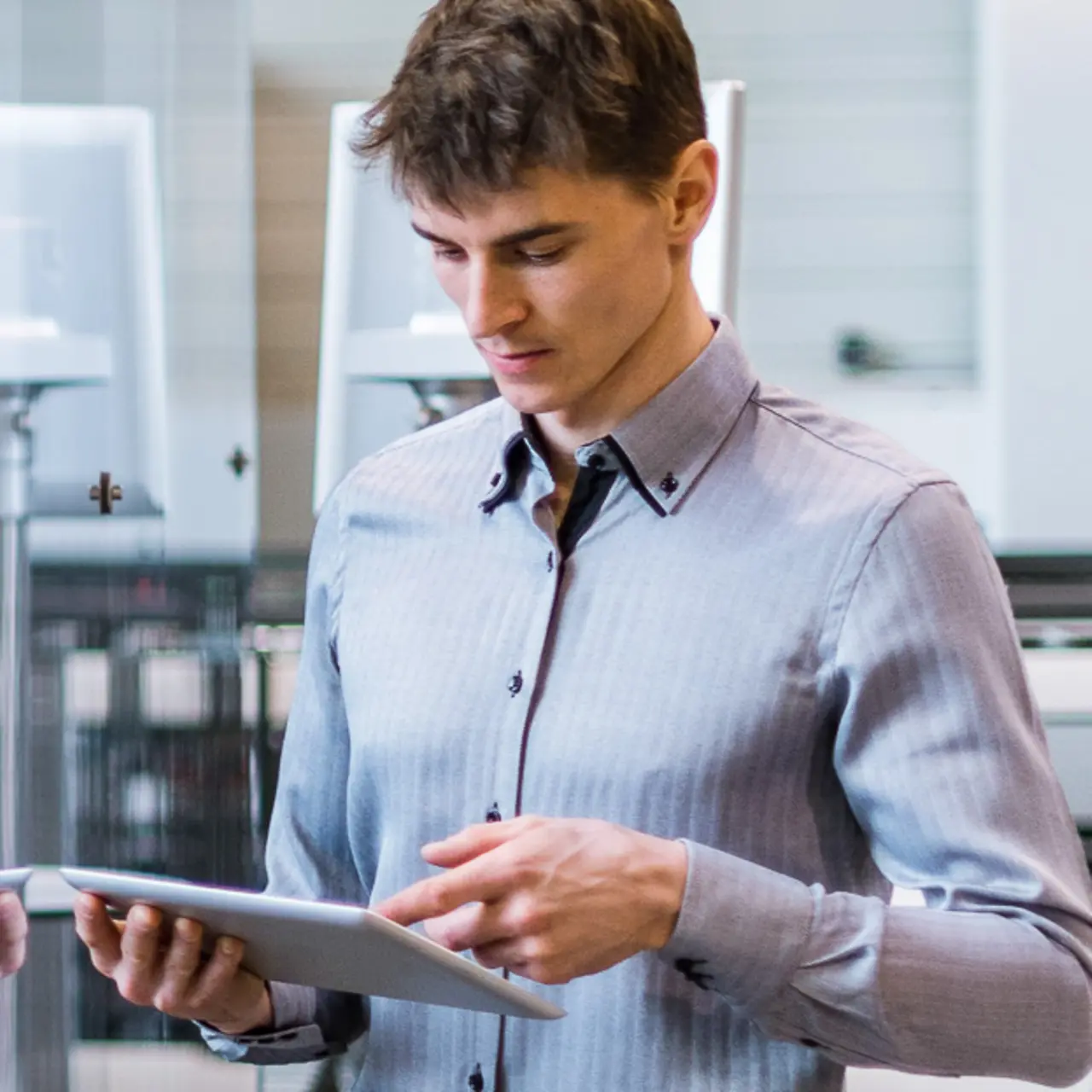Man with tablet in front of a conveyor belt with robot arm 