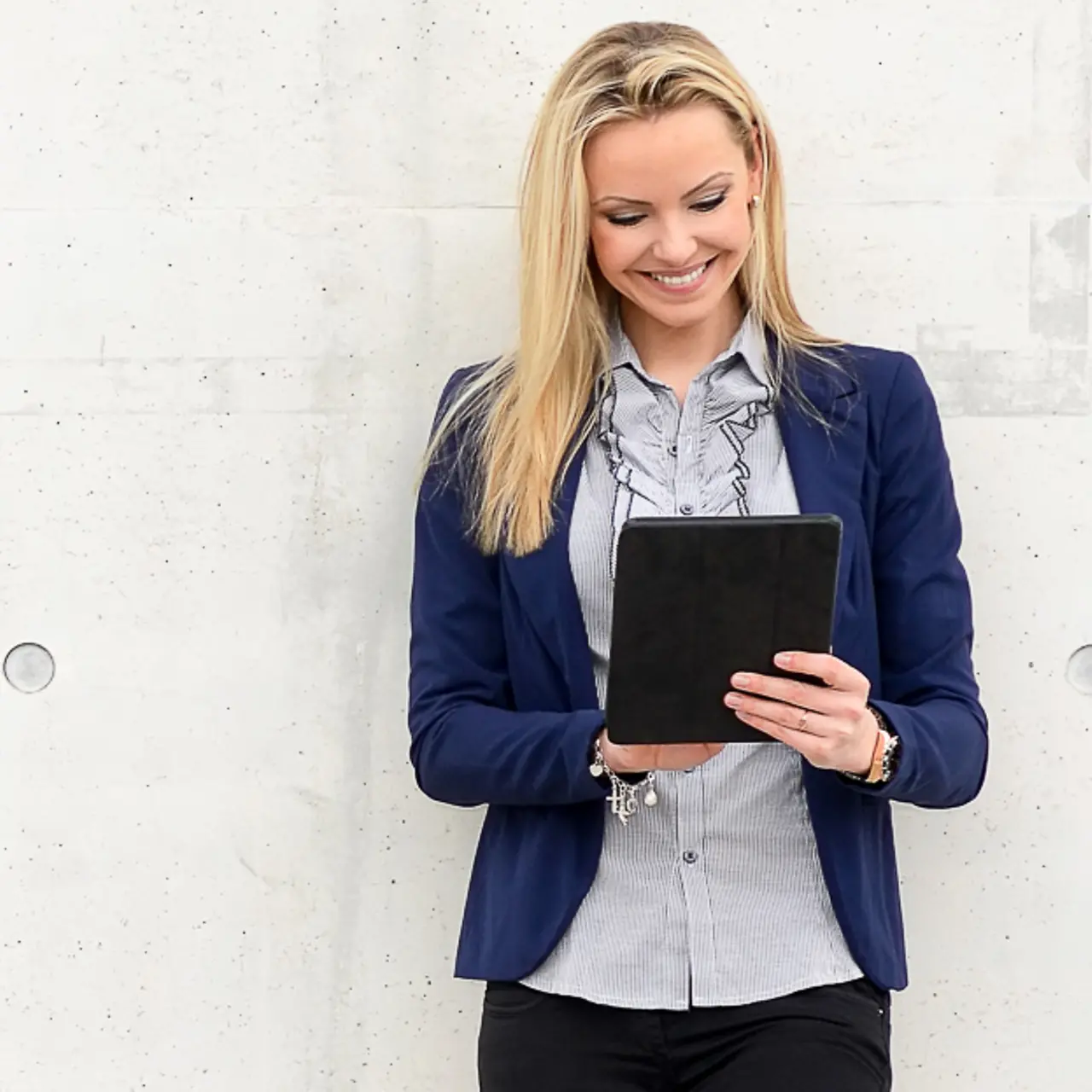 Woman leans on wall and gazes at a tablet smiling. Artistically generated constellation in the form of a padlock.