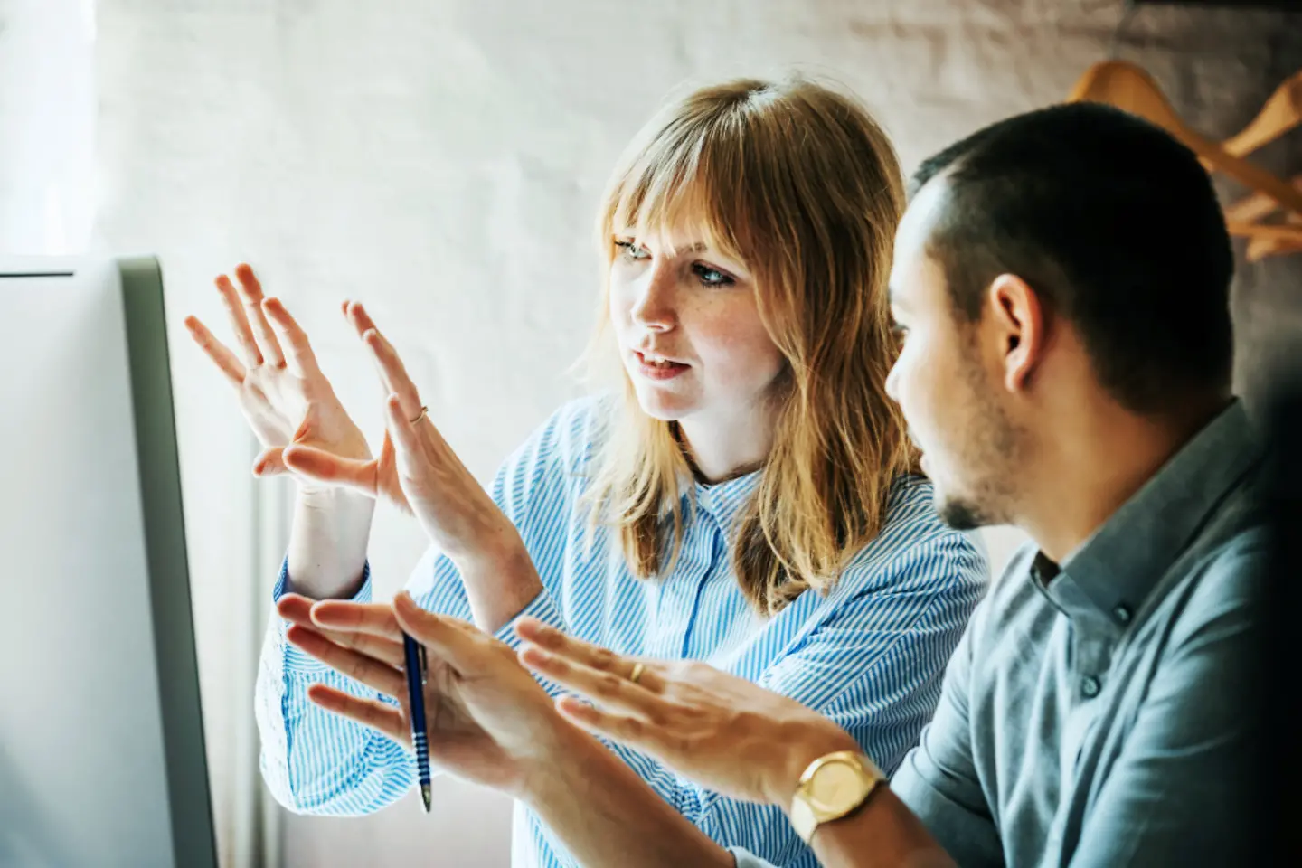 Two people looking at a screen and gesticulating to explain what they see.