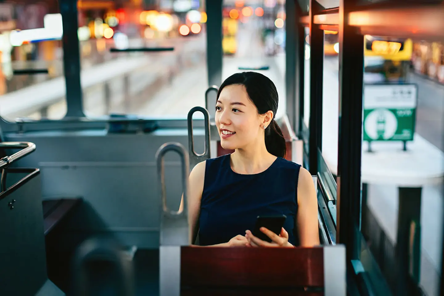 Frau mit Smartphone geniesst Stadtszene waehrend der Fahrt in oeffentlichen Verkehrsmitteln