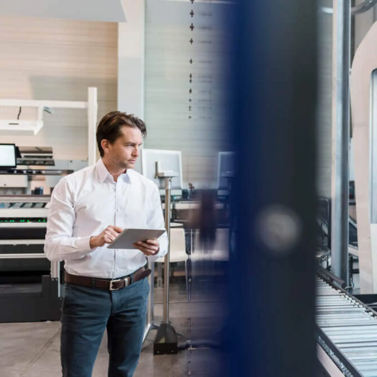 Geschaeftsmann mit Tablet am Fließband in einer Fabrik