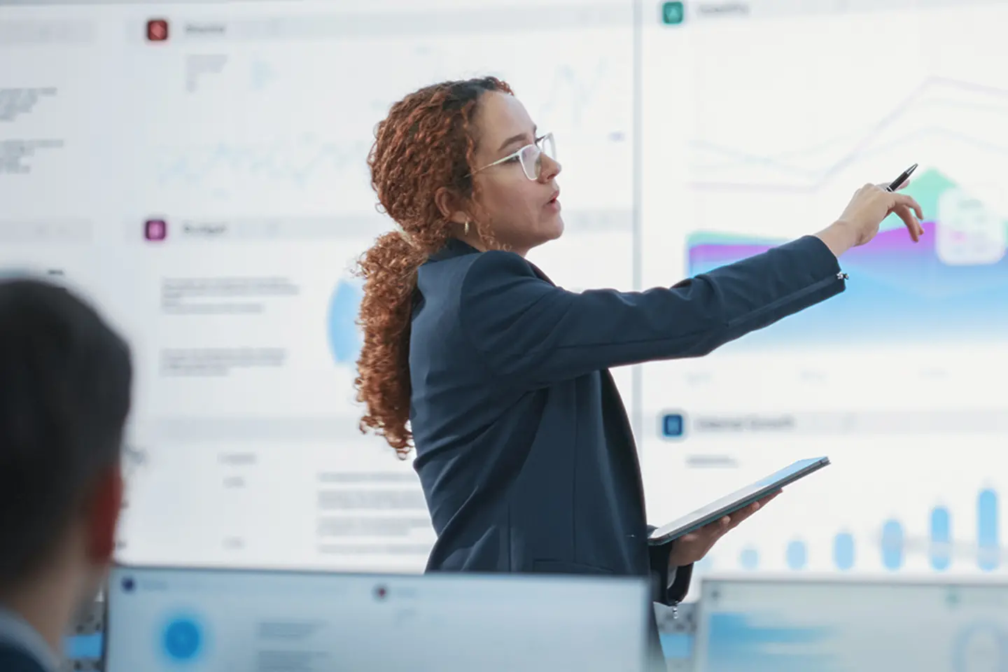 Científico de datos comprobando cifras financieras importantes frente a una gran pantalla digital