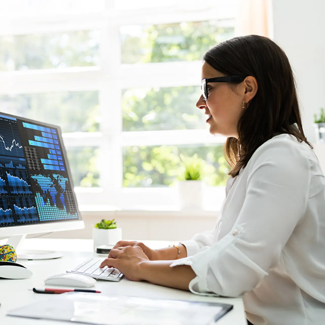 Female professional worker office worker at her desk in the home office with PC screen of data graphs