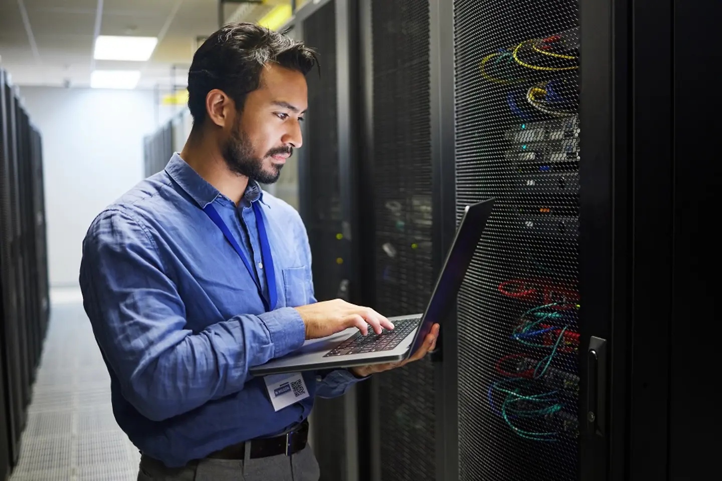 Un employé de l’informatique avec un ordinateur portable vérifie un serveur dans le datacenter